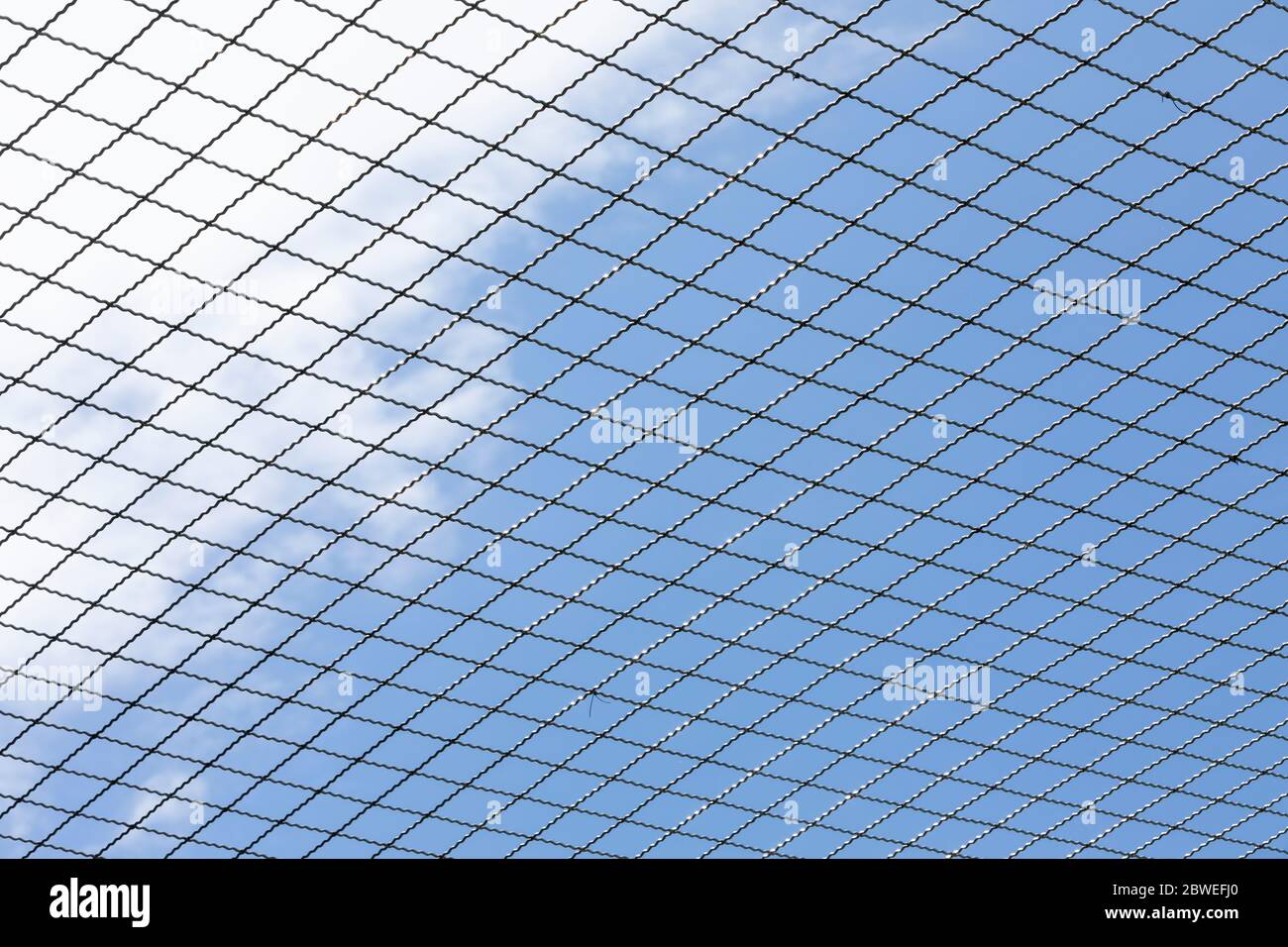 closeup of a new iron wire fence with blue sky in the back Stock Photo