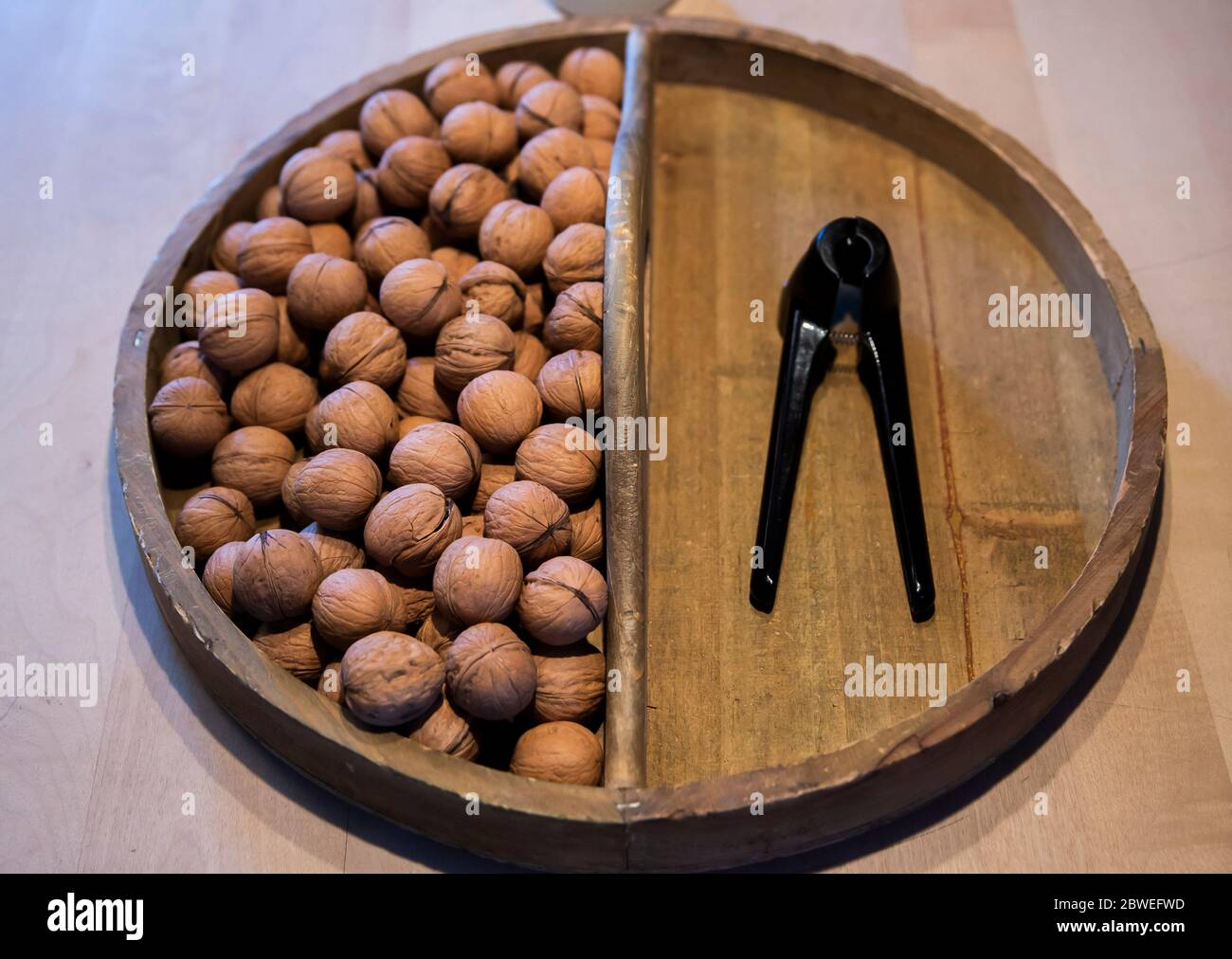walnuts and a nut cracker stored in an old round wooden bowl from a overhead view Stock Photo