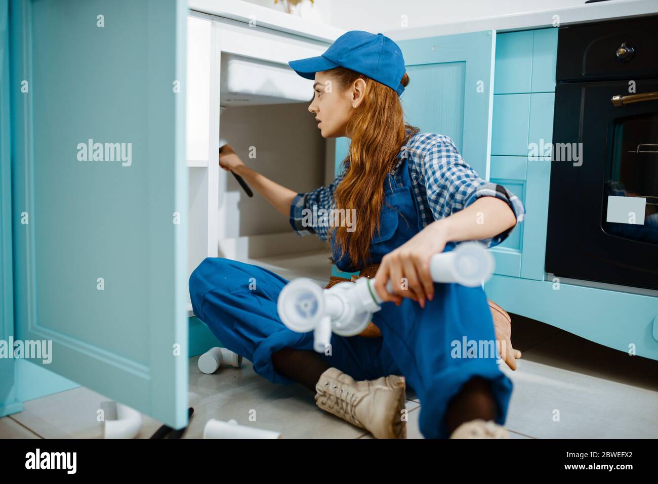 Female plumber fixing problem with drain pipe Stock Photo