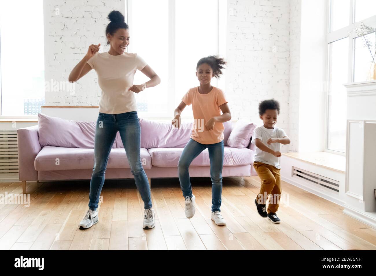 African mother teaches little children to dance in living room Stock Photo