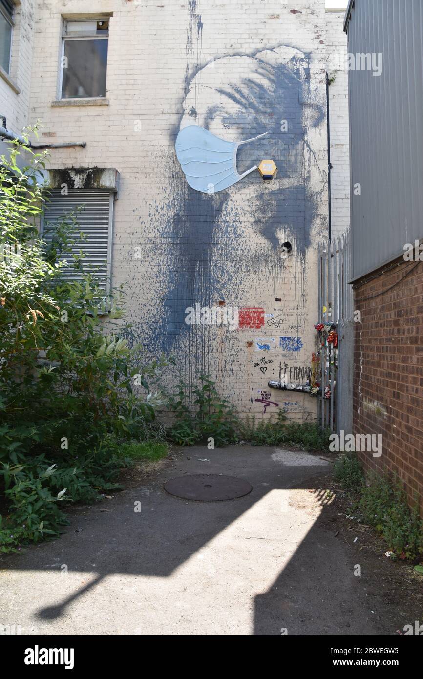 Banksy Graffiti The Girl with the Pierced Eardrum with blue face mask (covid-19). Albion Dockyard, Hanover Place, Bristol Stock Photo