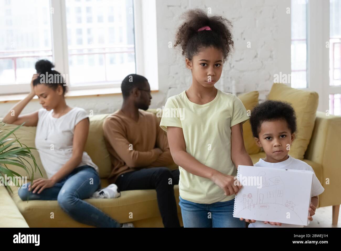 Unhappy little African children holding drawing suffers from parents divorce Stock Photo