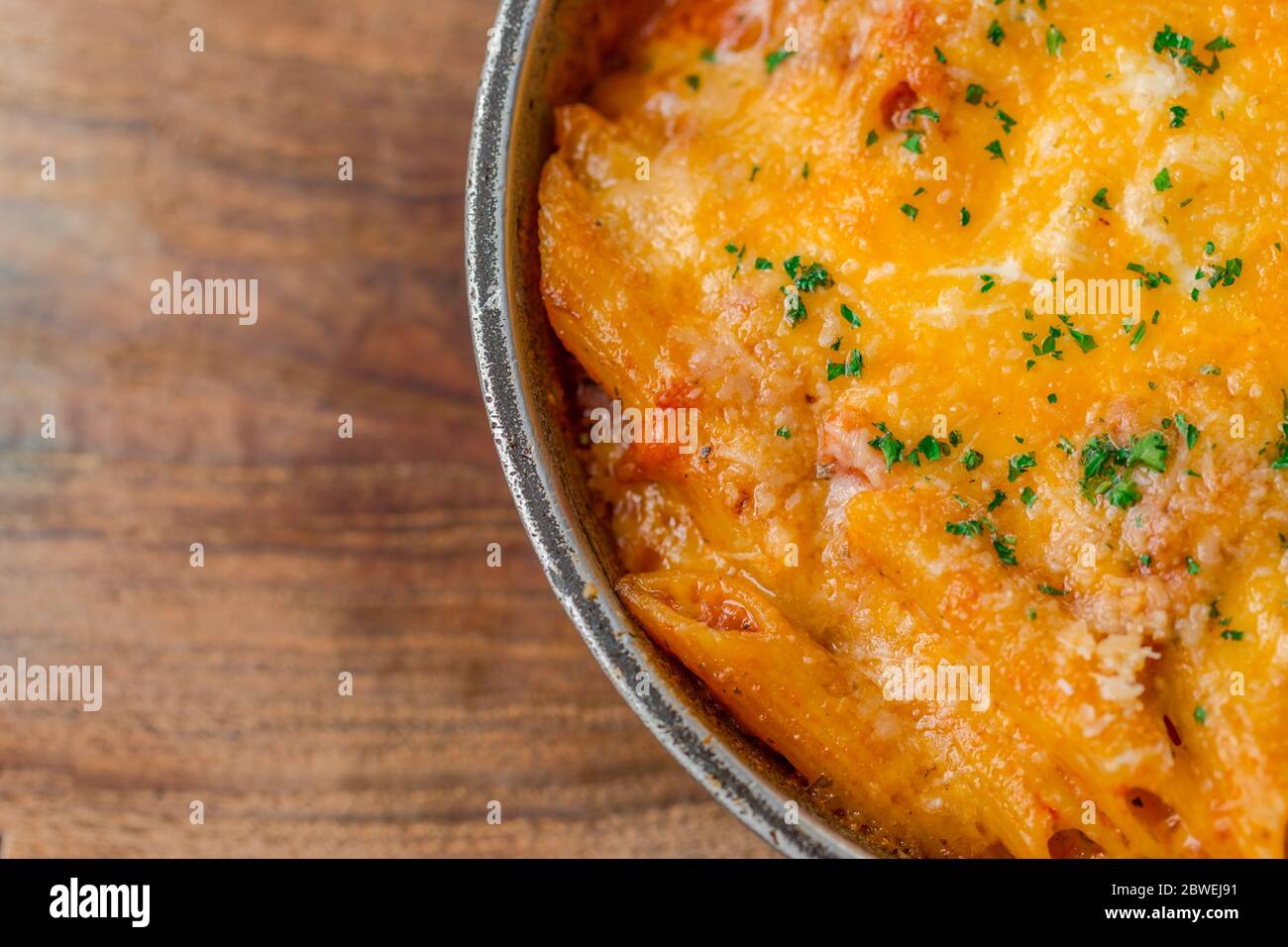 Baked pasta on wooden plate, basil with penne. Italian food background Stock Photo