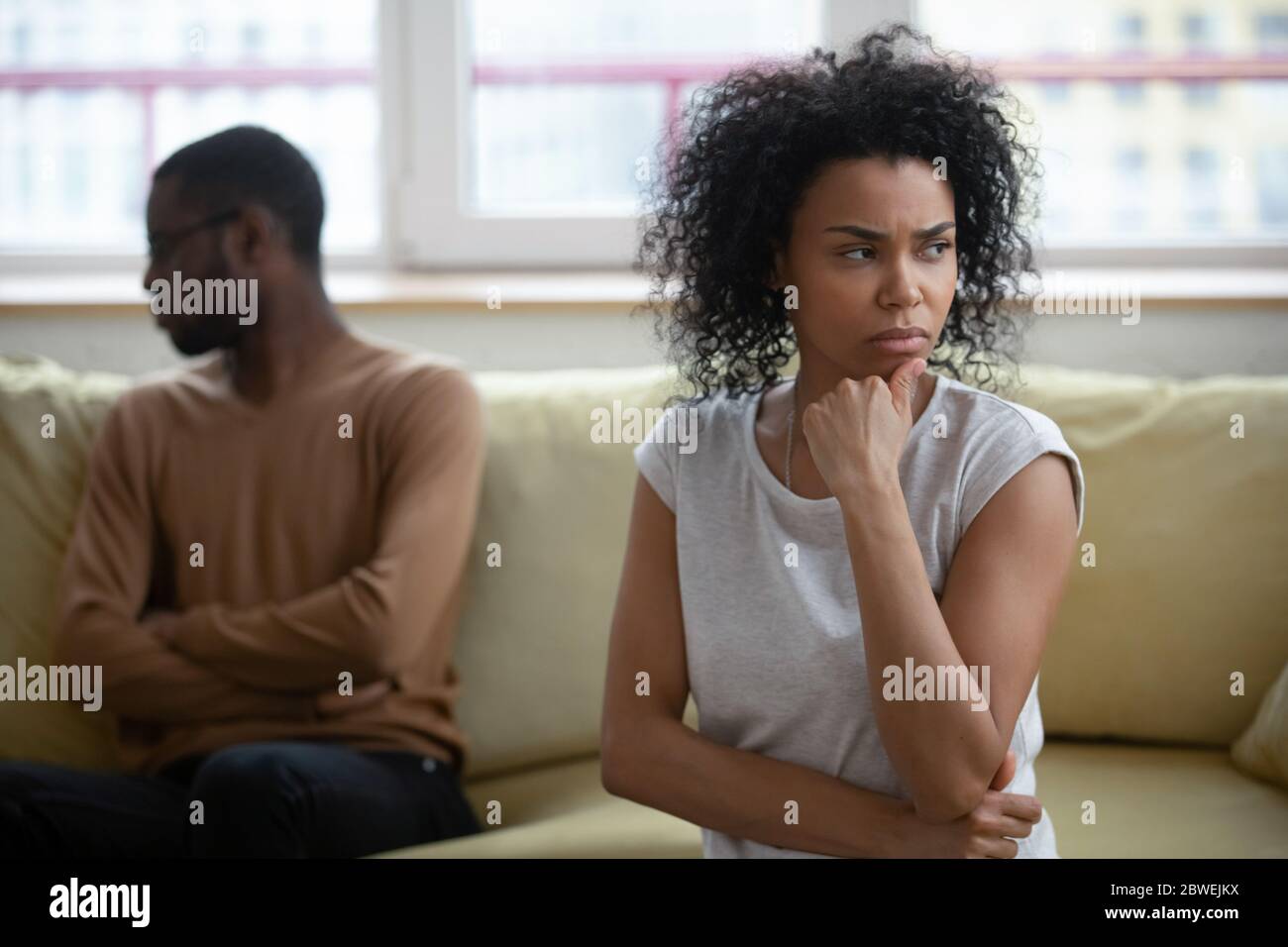 African couple sitting apart thinking about relations problems Stock Photo