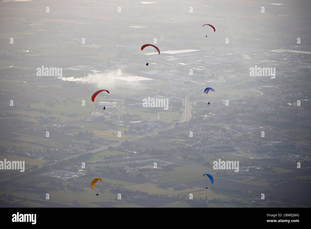 colourful hang gliders in flight over Assisi, Italy Stock Photo