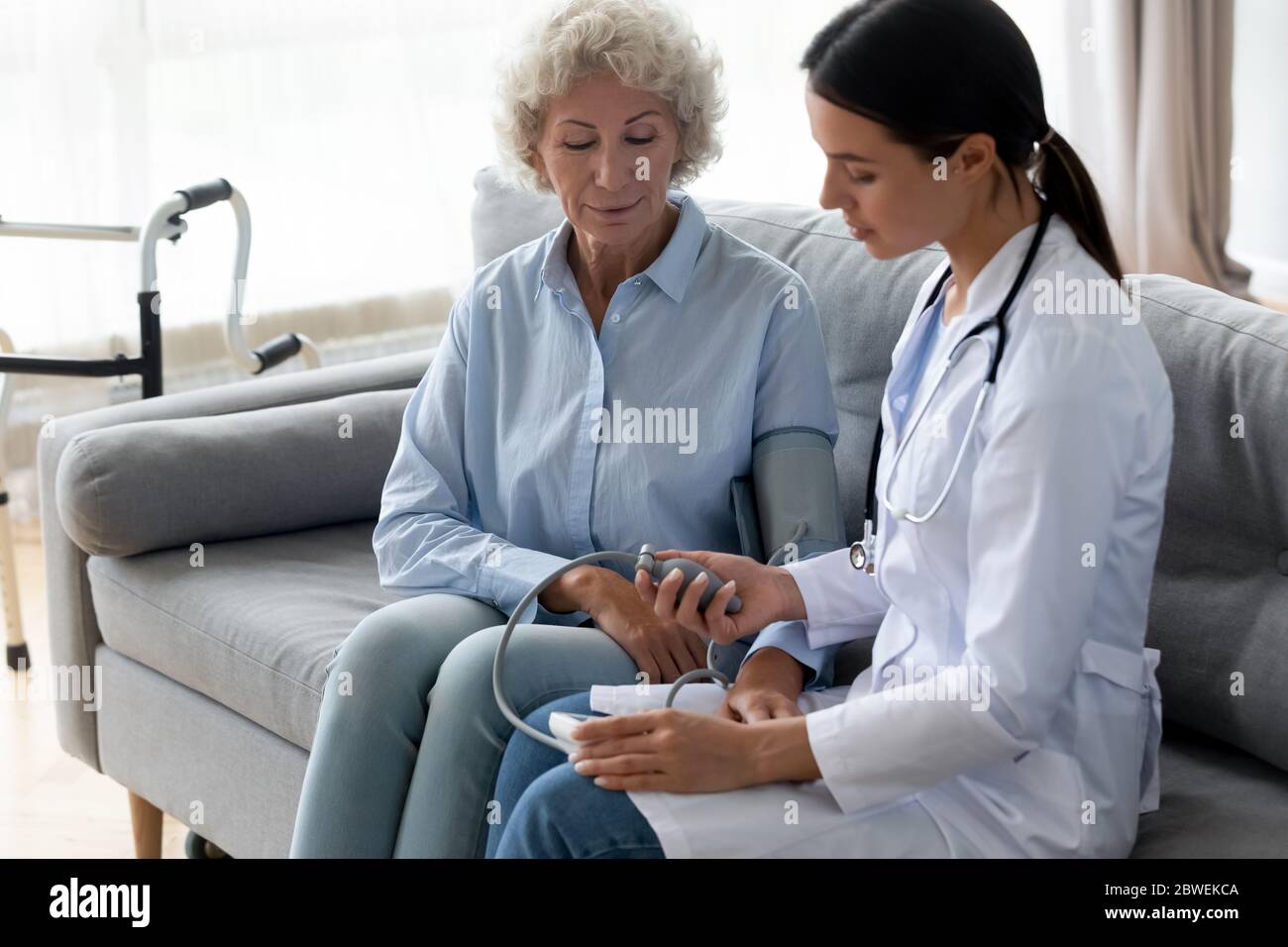 Physician manually takes blood pressure to elderly woman patient Stock Photo