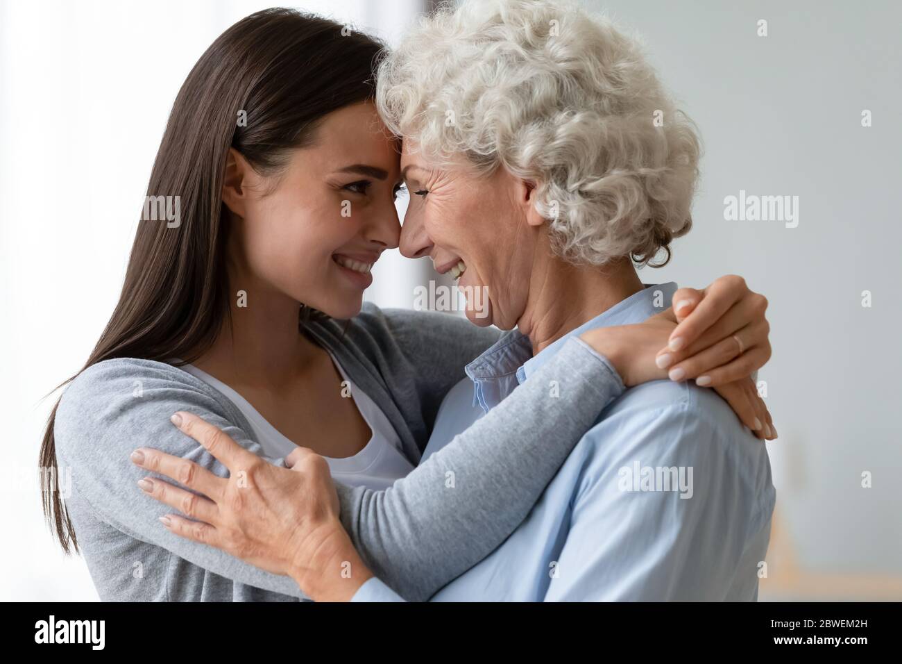 Pretty retired grandmother and grownup granddaughter touch noses showing affection Stock Photo