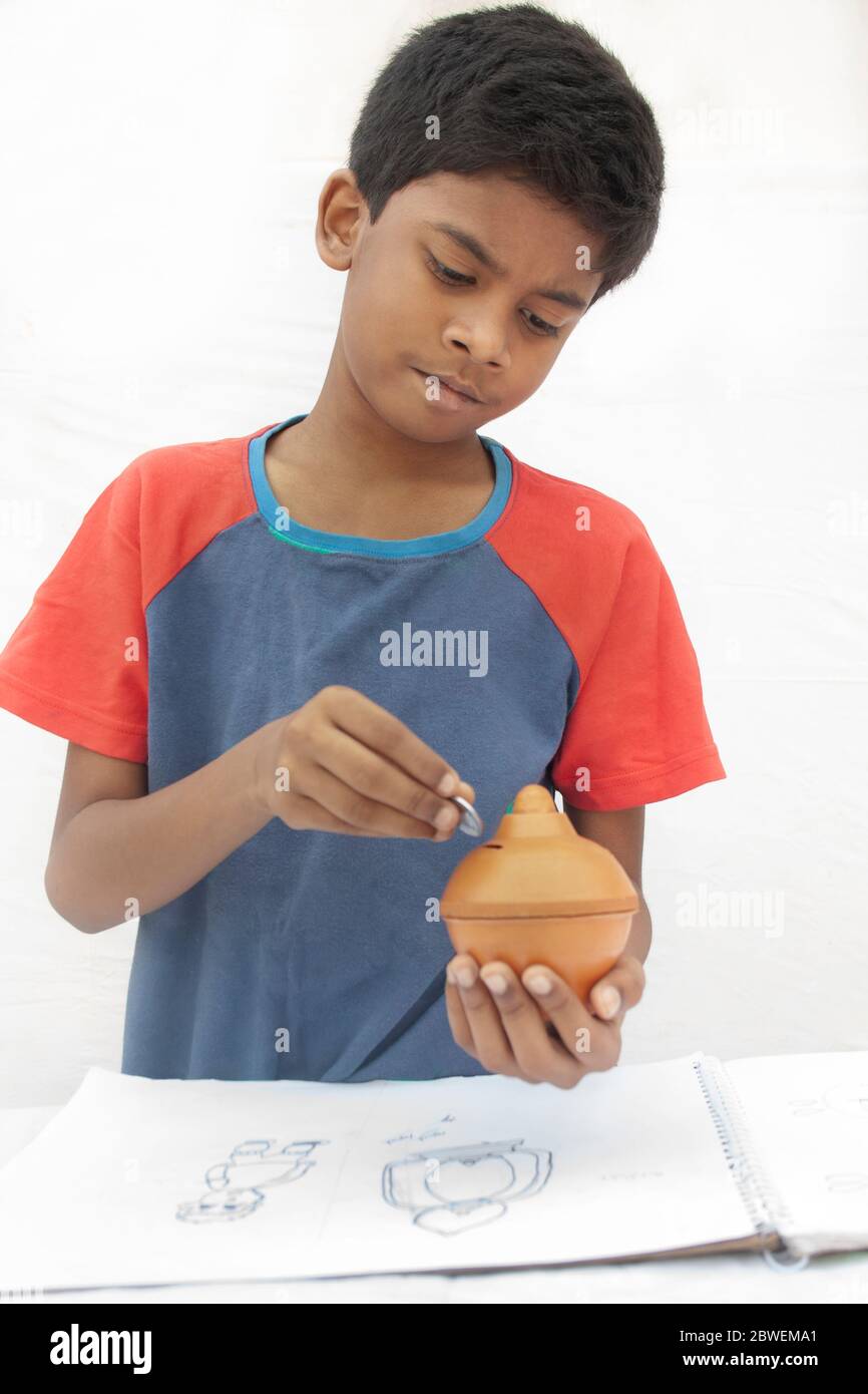Close-up Boy putting coins into piggy bank Stock Photo - Alamy