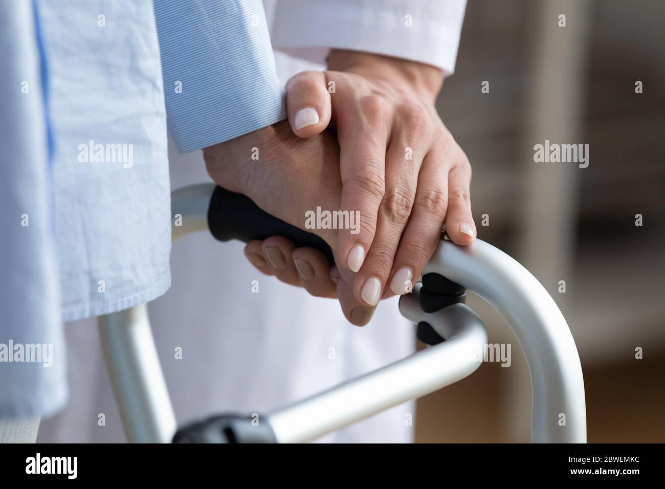 Physiotherapist touches woman hand while she holding walking frame closeup Stock Photo