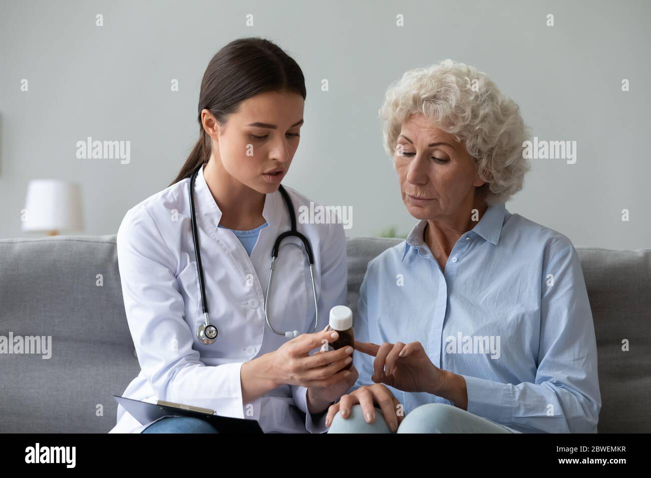 Nurse explain antibiotic pill dosage to old woman patient indoors Stock Photo