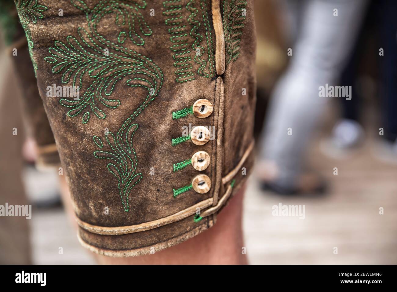 close up of a traditional austrian leather pants with green embroidery and stag horn button Stock Photo