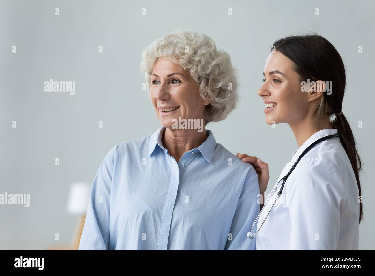 Nurse puts hand on shoulder of elderly patient showing care Stock Photo