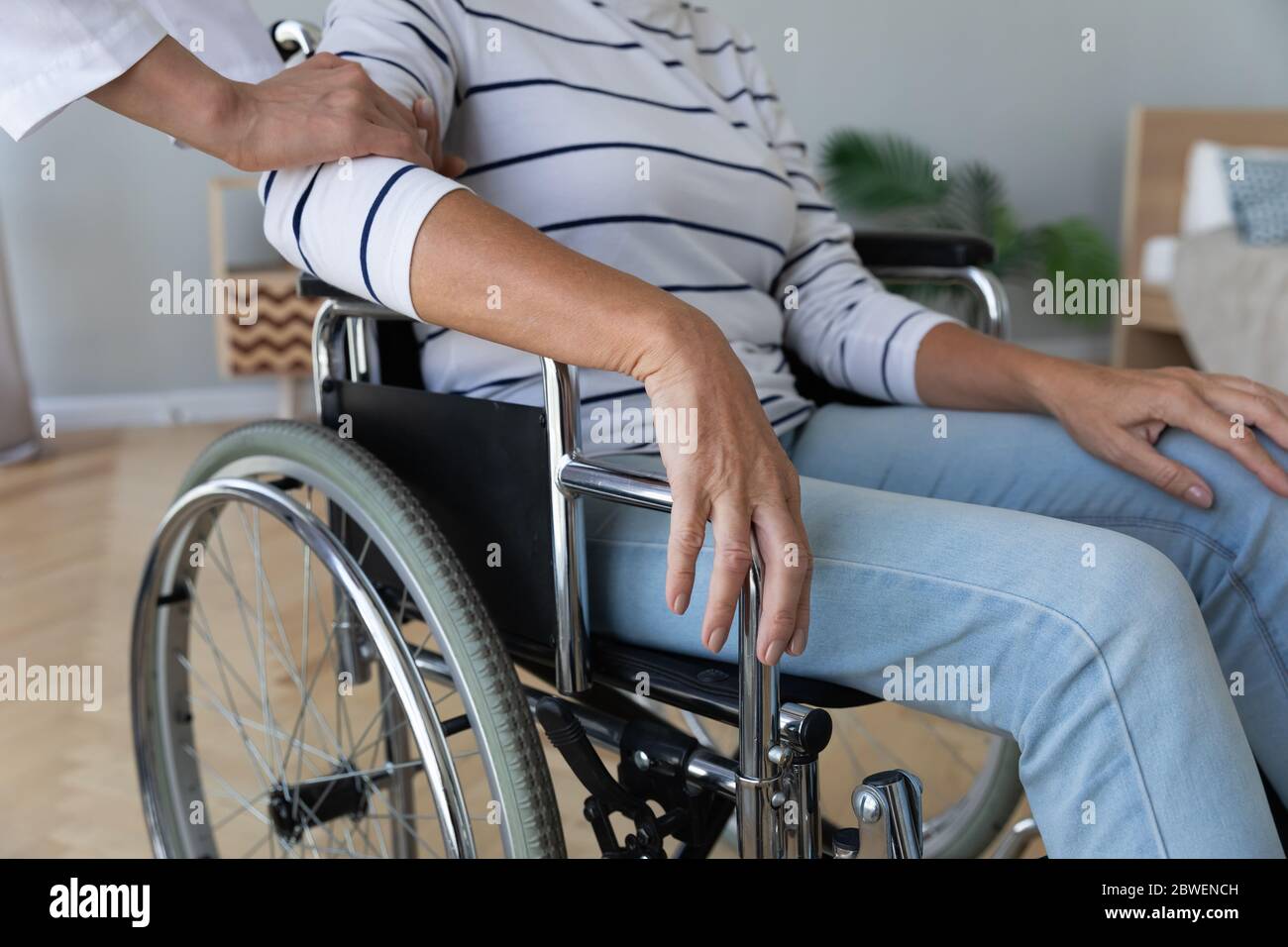Nurse touch hand of elderly disabled woman in wheelchair closeup Stock Photo