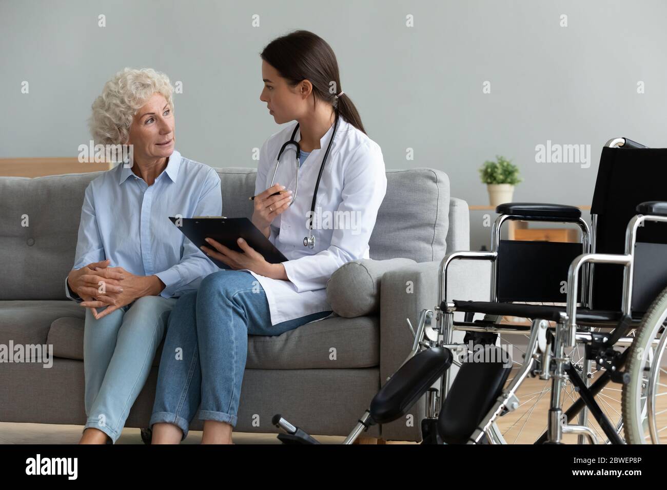 Doctor consulting disabled aged patient explain diagnosis during visit Stock Photo