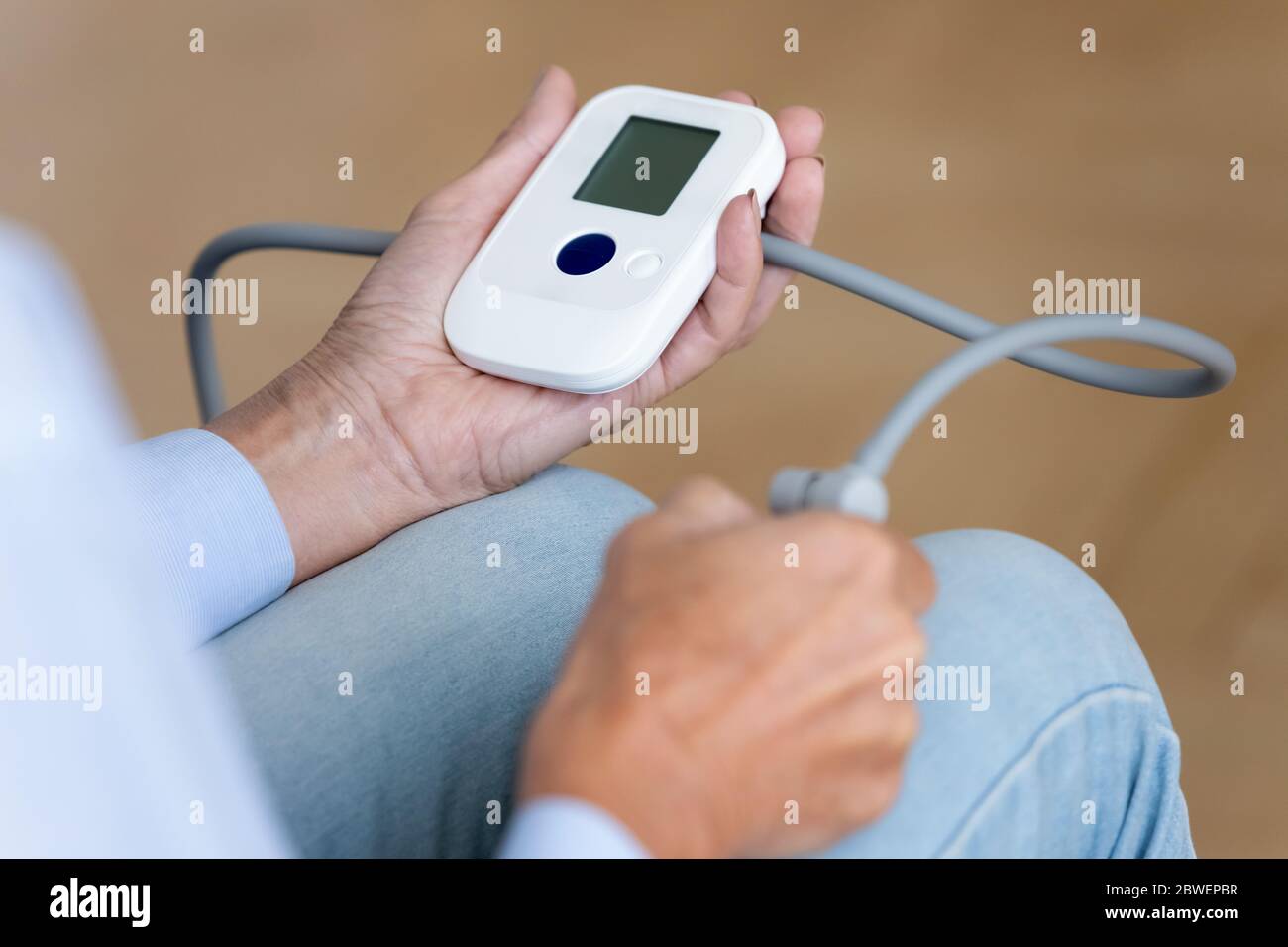 Elderly woman monitoring blood pressure using sphygmomanometer device