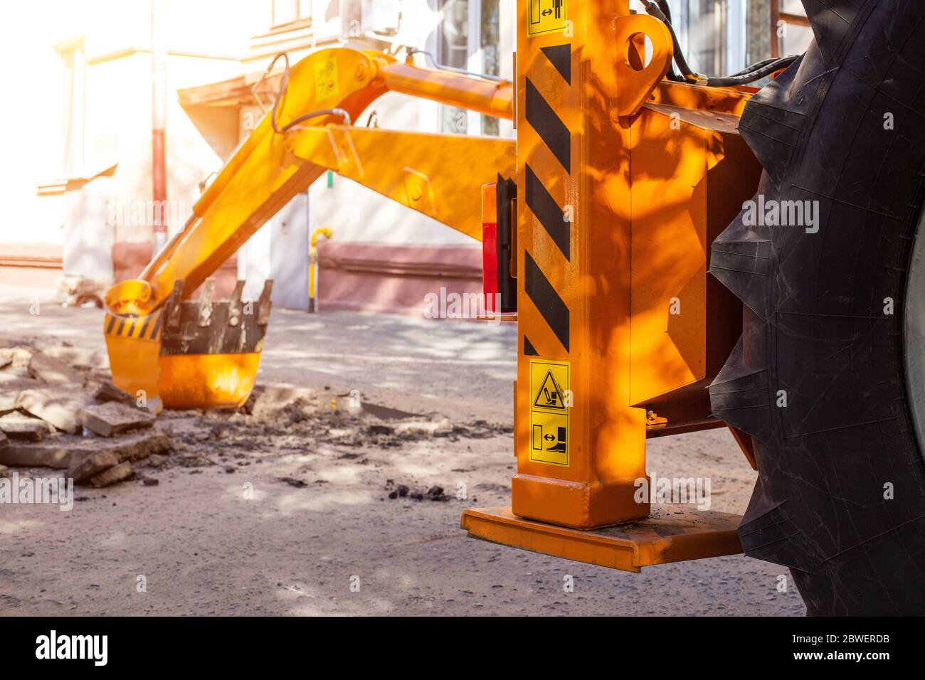 An excavator's rear bucket digs in the courtyard of a residential building. Laying gas and water supply, replacing old pipes, accident, renovation Stock Photo