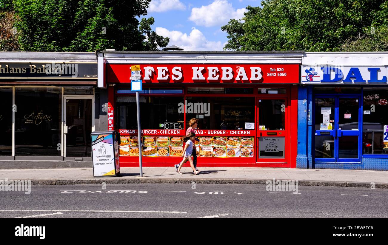 Anonymous Woman And Daughter Walking Past A Takeaway Kebab Shop Stock Photo