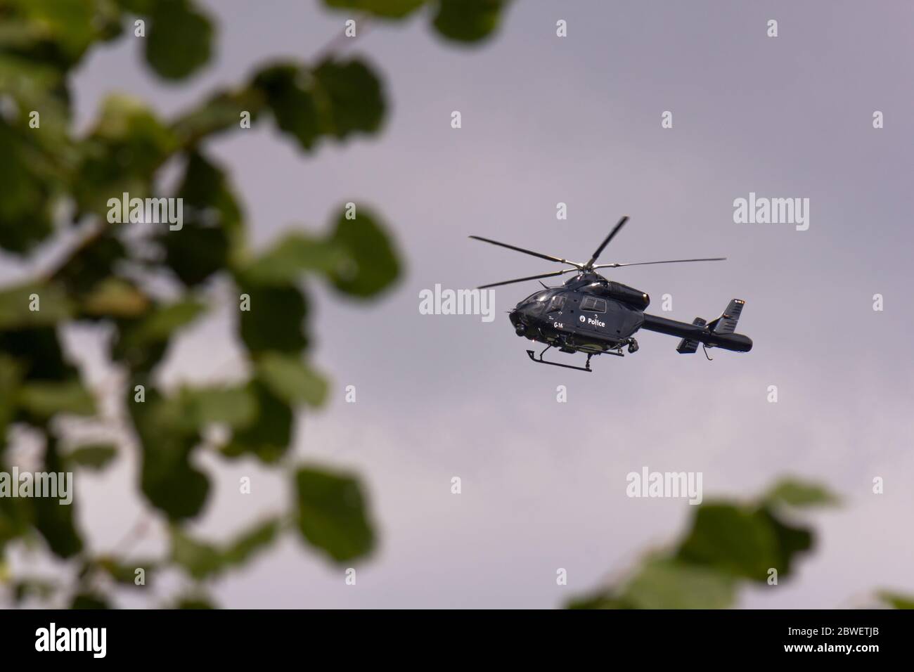 Airborne police helicopter (G-16) against cloudy sky. Stock Photo