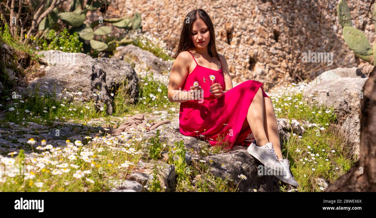 Young woman enjoying the view and the sunlight on her face on a rural flower bed with daisy blossoms Stock Photo