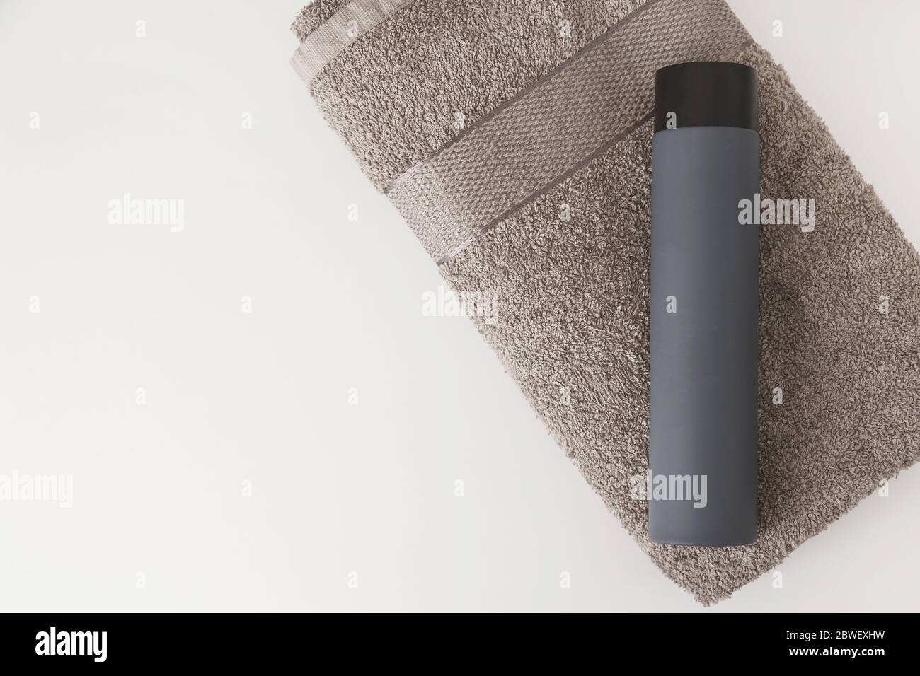 Male shampoo gray bottle on cotton towel isolated on white background