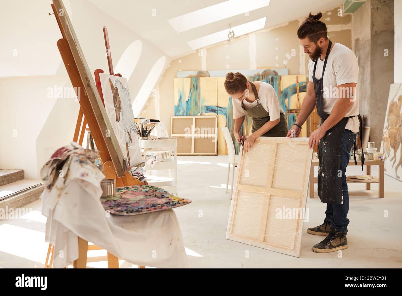 Full Length Portrait Of Two Contemporary Artists Wrapping Painting For Shipping While Standing In Spacious Art Studio Lit By Sunlight Copy Space Stock Photo Alamy