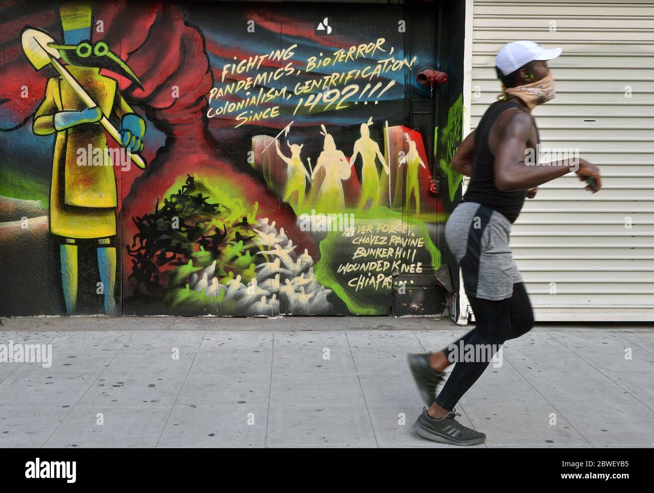 A man jogs past a mural noting that pandemics in America go back to 1492 in downtown Los Angeles on the sixth day of protesting the killing of George Floyd on Sunday, May 31, 2020. The National Guard was deployed to back up the LAPD after Gov. Gavin Newsom declared a state of emergency Saturday for all of Los Angeles County, and are expected to be part of the city's response to ongoing unrest and demonstrations against police brutality following the in-custody death of George Floyd in Minneapolis on Memorial Day. Photo by Jim Ruymen/UPI Stock Photo