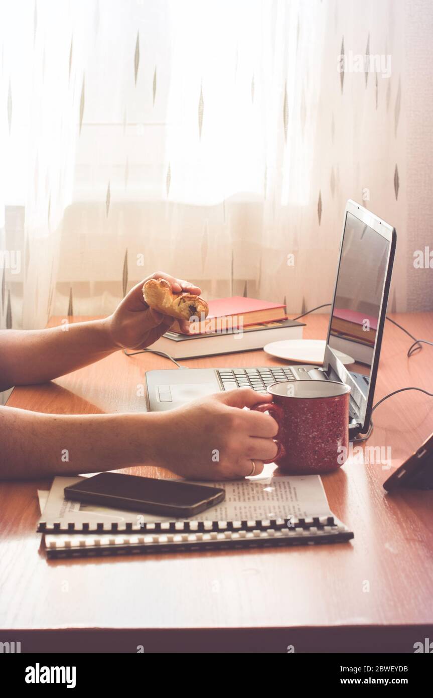 Man working from home. Using computer and eating donuts. Distance work ...