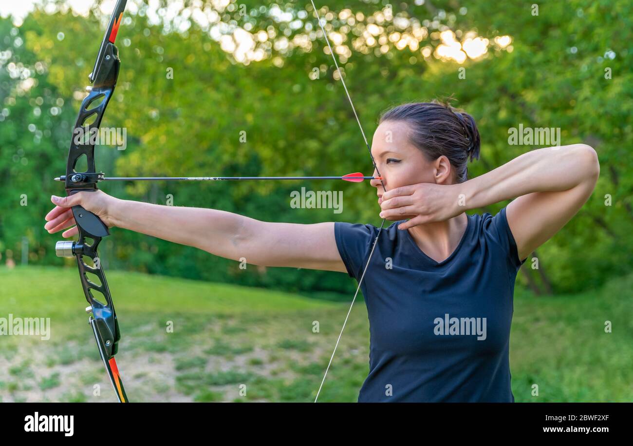 archery, young woman with an arrow in a bow focused on hitting a target