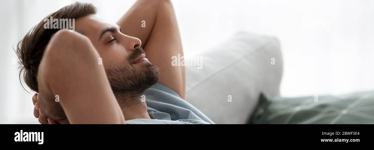 Calm man puts hands behind head resting on couch closeup Stock Photo