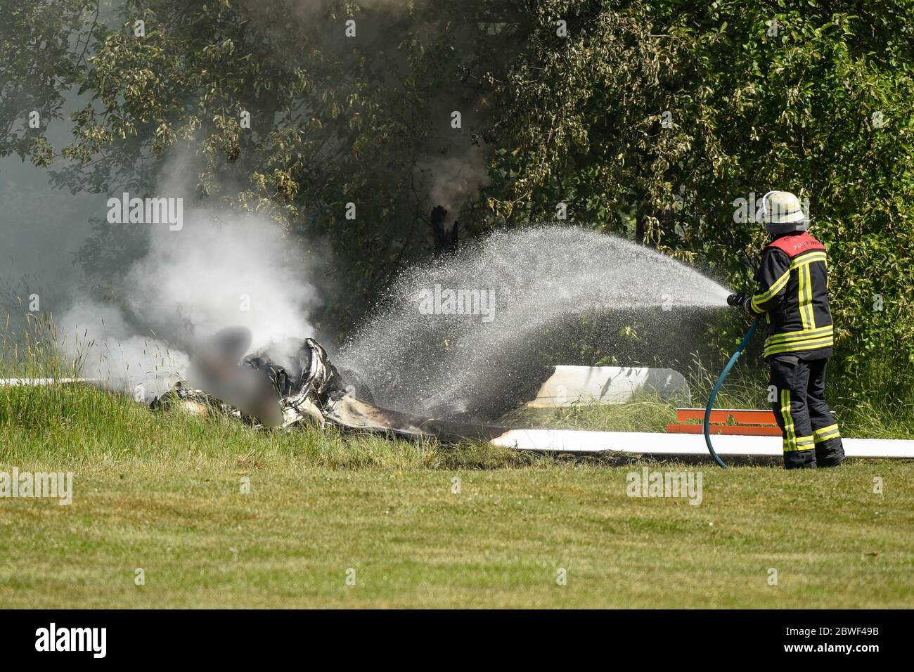 Fulda, Germany. 01st June, 2020. A fireman extinguishes the last remains of embers at the crash site of a glider. The pilot died in the crash. The plane crashed in an allotment garden late this morning for unknown reasons, police said. Credit: Hendrik Urbin/Osthessen News/dpa - ATTENTION: Graphic Content pixelated/dpa/Alamy Live News Stock Photo
