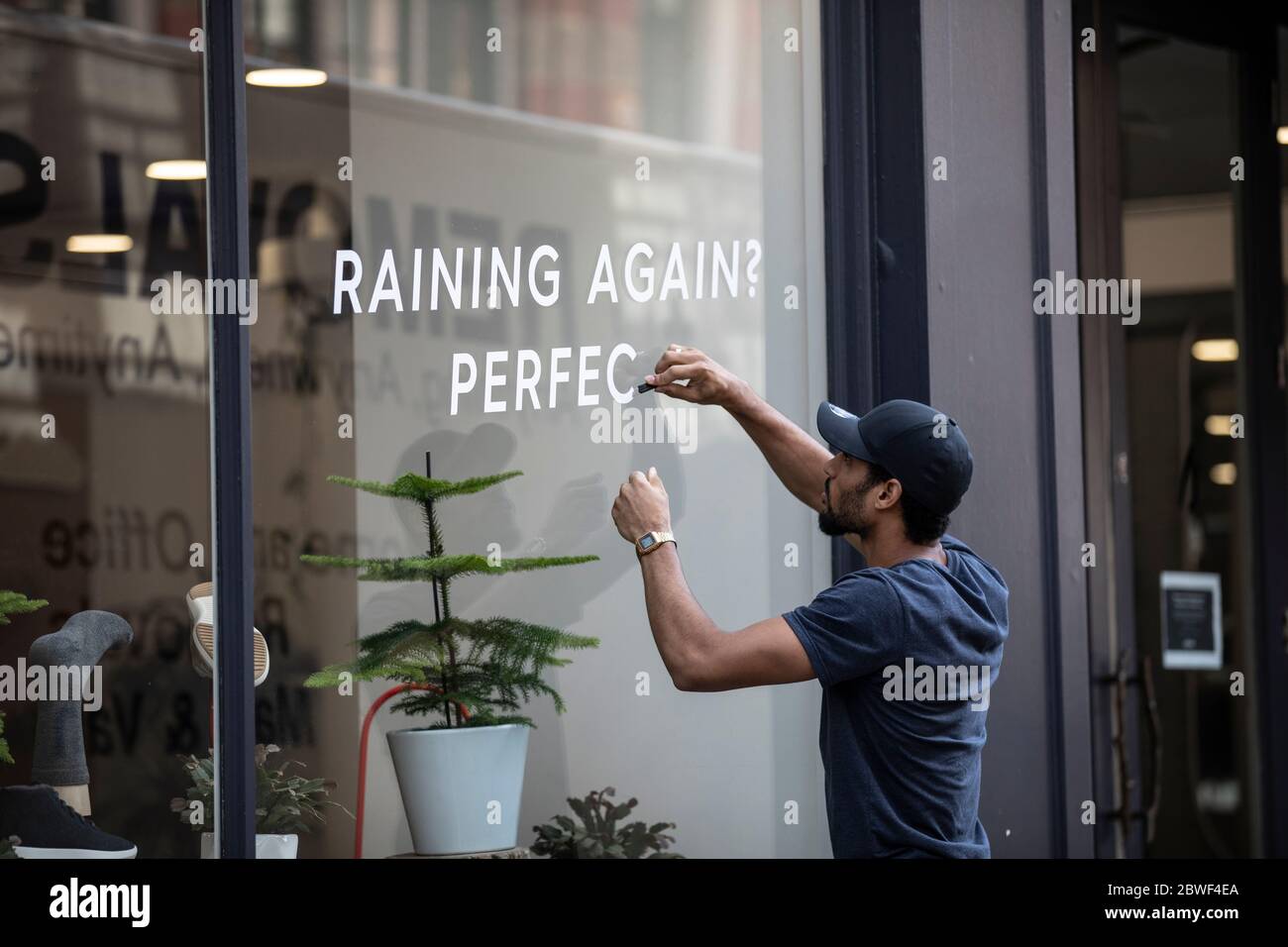 A worker prepares a shop window as non-essential stores on the high street are set to reopen after the UK coronavirus lockdown is relaxed, London, UK Stock Photo