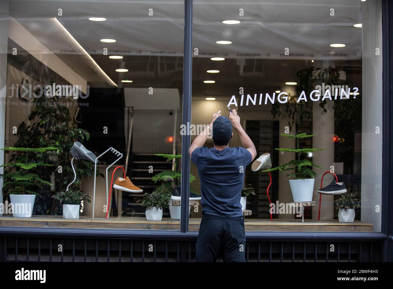 A worker prepares a shop window as non-essential stores on the high street are set to reopen after the UK coronavirus lockdown is relaxed, London, UK Stock Photo