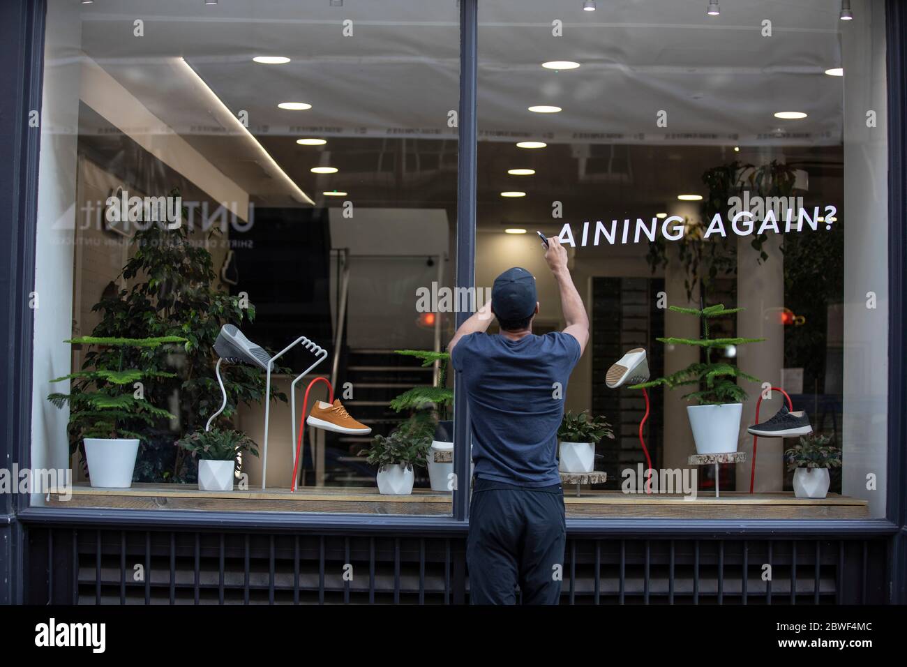 A worker prepares a shop window as non-essential stores on the high street are set to reopen after the UK coronavirus lockdown is relaxed, London, UK Stock Photo