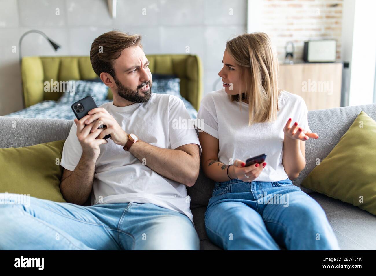 Jealous woman spying boyfriend and watching his mobile phone Stock Photo