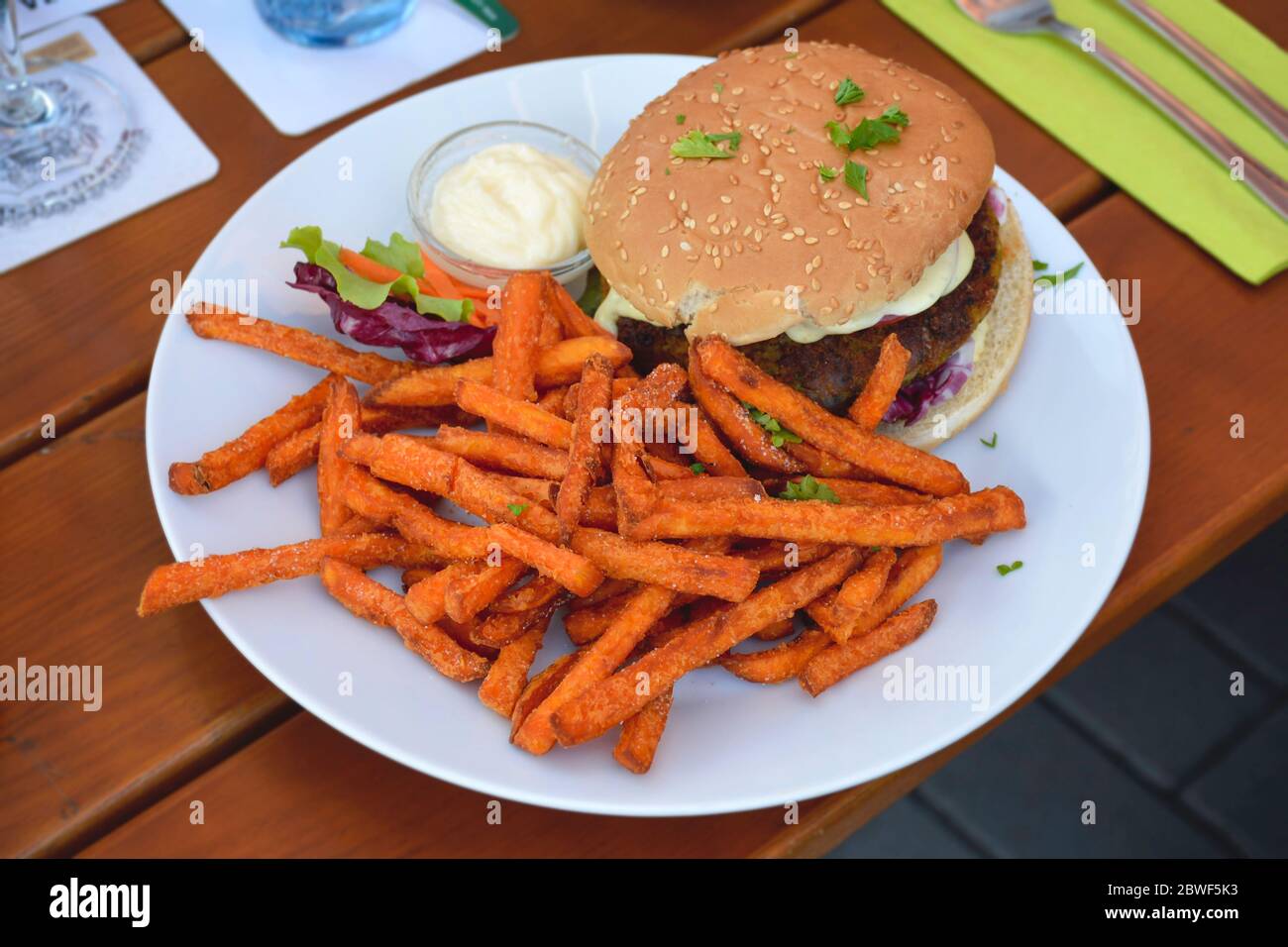 Healthy vegetarian burger with sweet potato fries served with some lettuce on a plate. Stock Photo