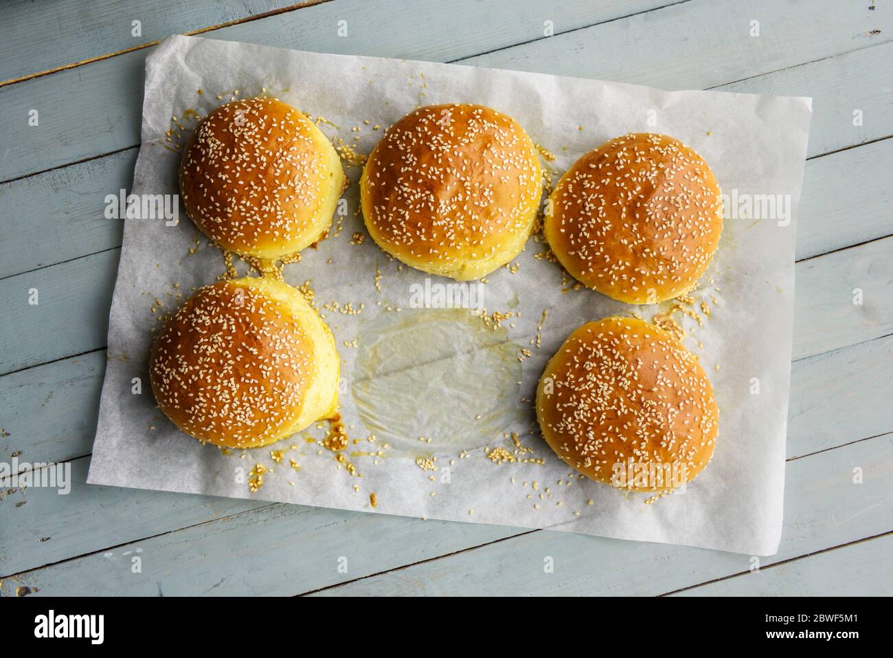 Homemade burger bun on bakery parchment on wooden table. Food photography Stock Photo