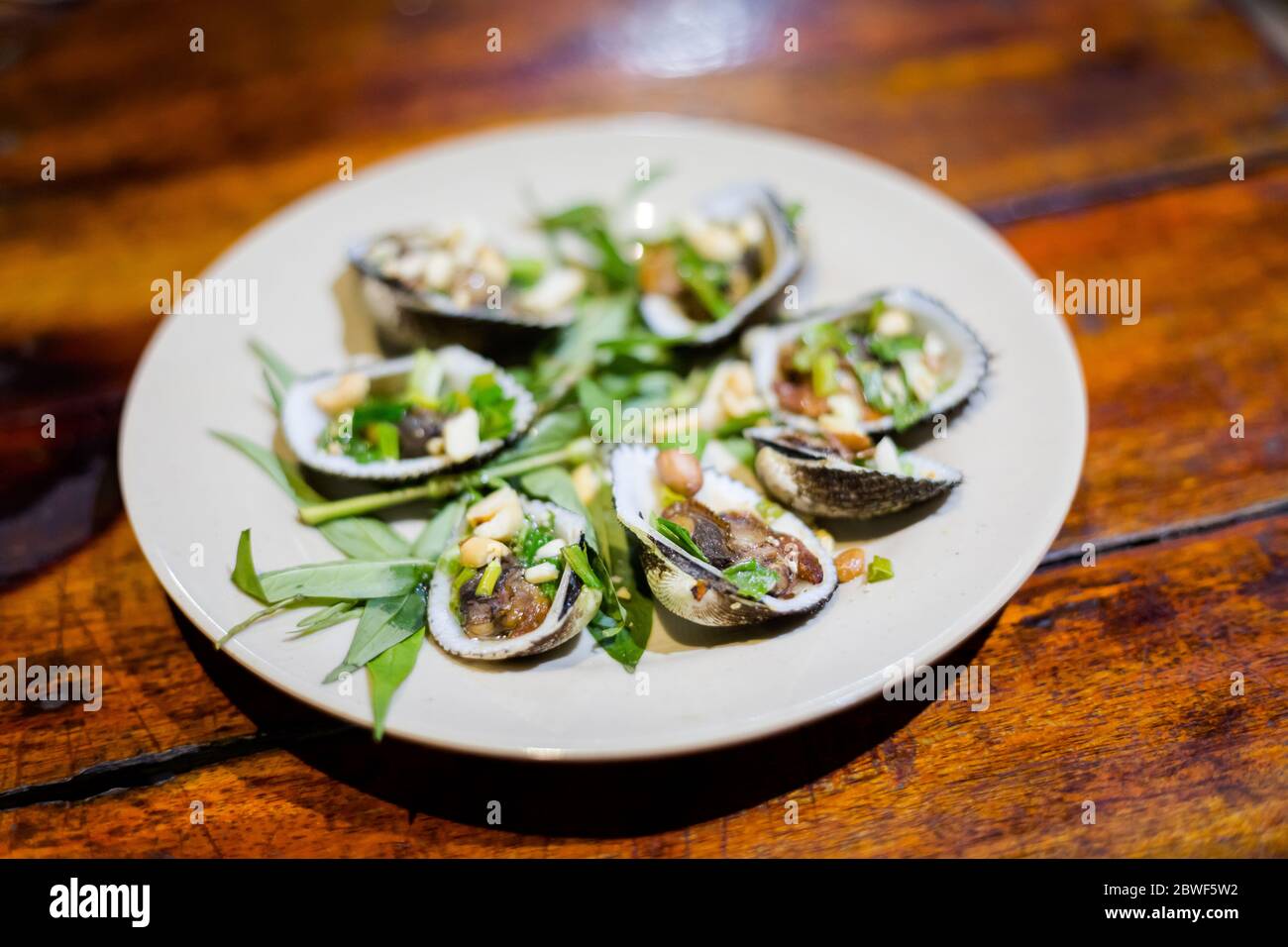 Delicious fresh prepared mussels, clams. Traditional vietnamese cuisine served in harbour restaurant on Phu Quoc, Vietnam. Stock Photo