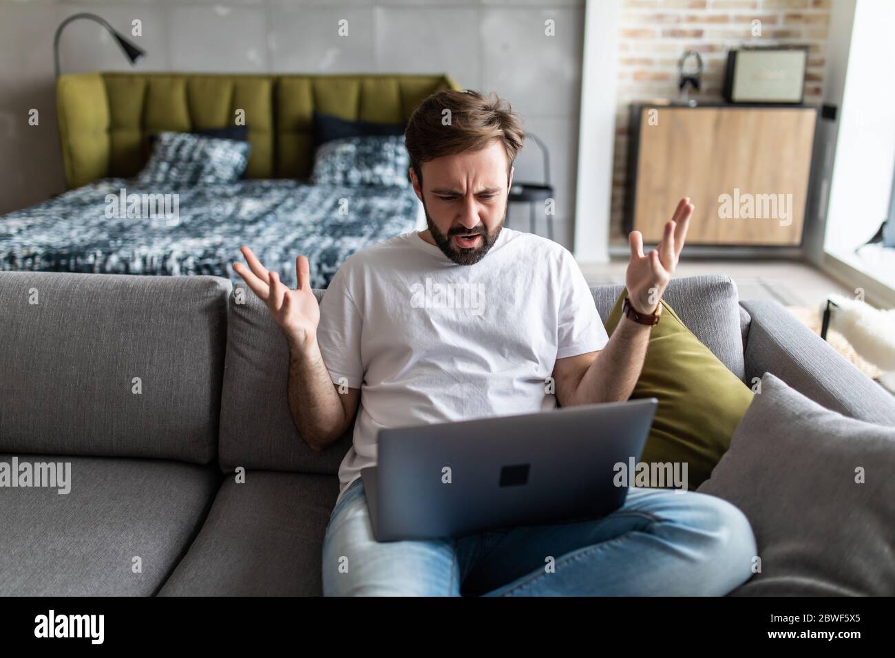 Outraged angry man reading bad news, looking at screen, having problem with broken laptop Stock Photo
