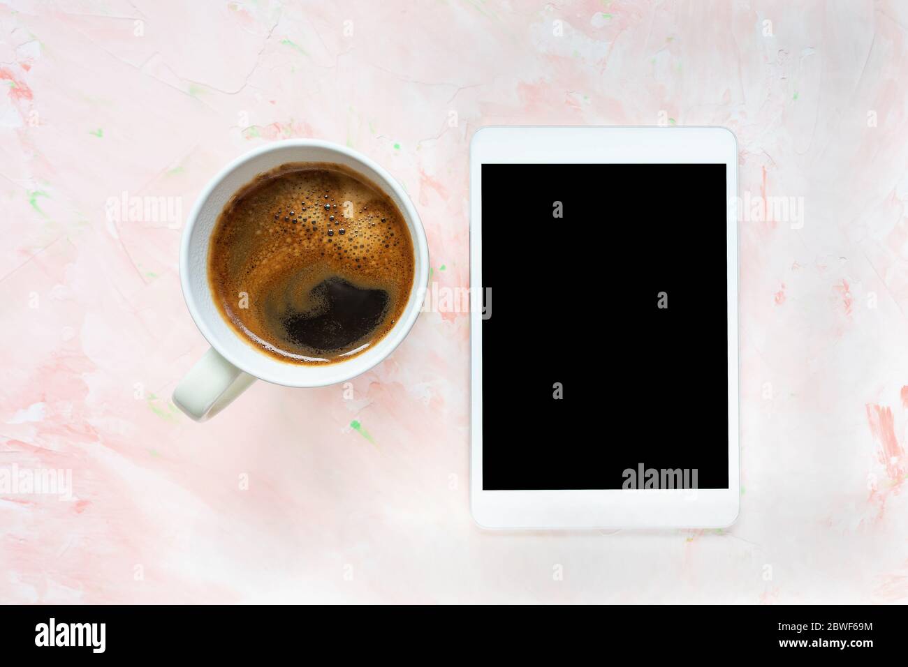 Cup of black coffee and tablet on pink background Stock Photo