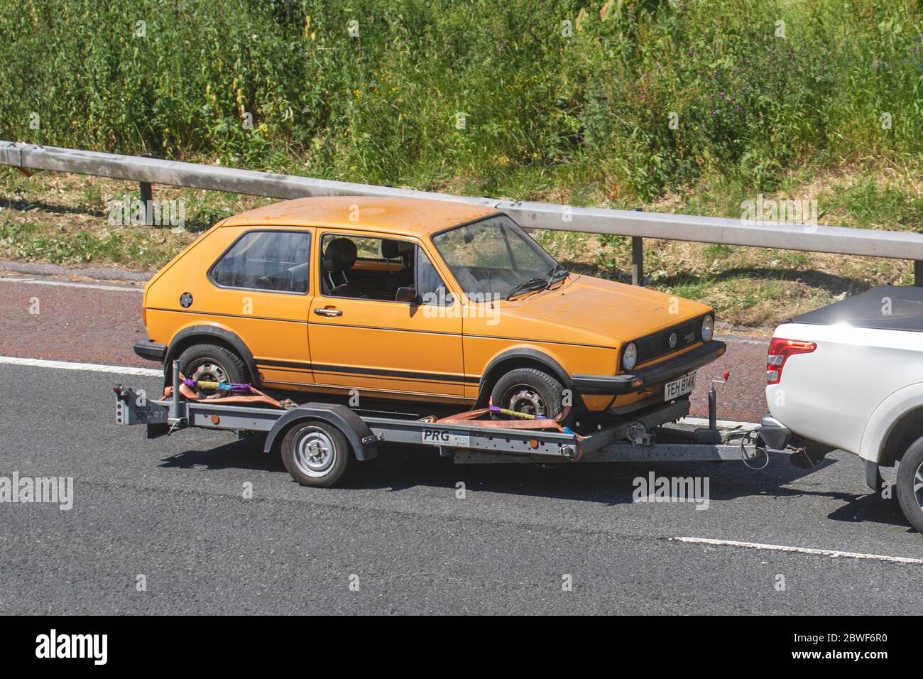 1981 orange Volkswagen Golf Driver; VW restoration project rare barn find, vehicle restoration project, restore old wreck, classic car on car trailer; UK Vehicular traffic, transport, saloon cars, automotive history on the 3 lane M6 motorway highway. Stock Photo