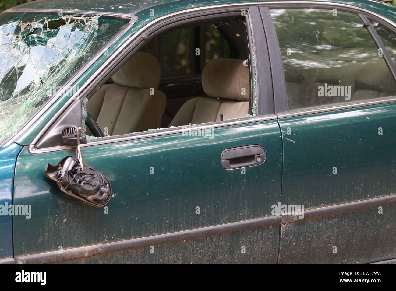 Abandoned car with broken windshield and side windows, flat tires and