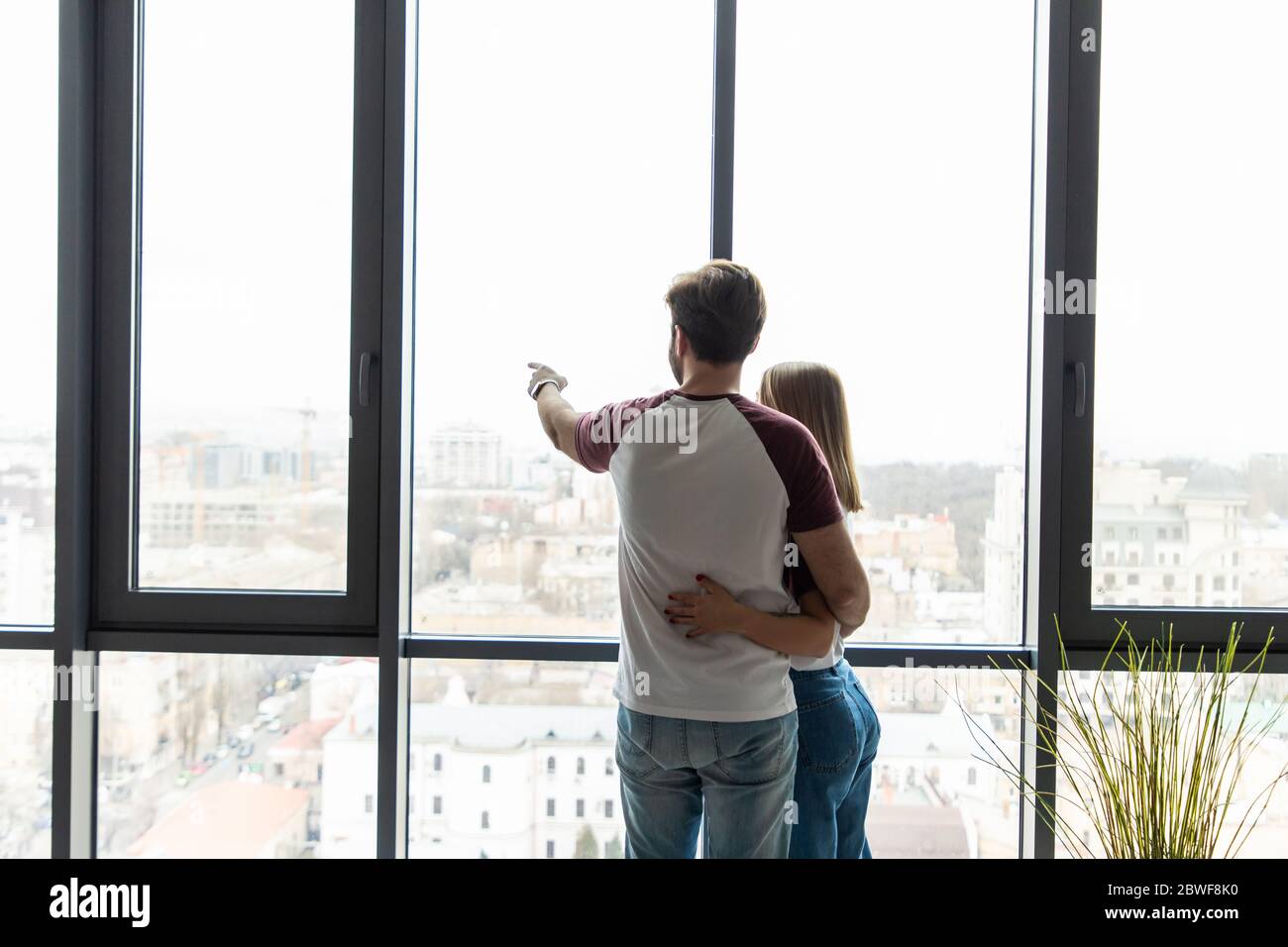 Back view of beautiful young business couple hugging while looking out ...