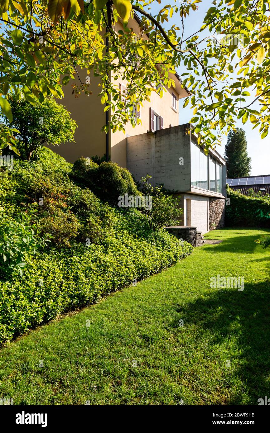 Beautiful house in the middle of the greenery with a modern reinforced concrete connection and a large window. Stock Photo