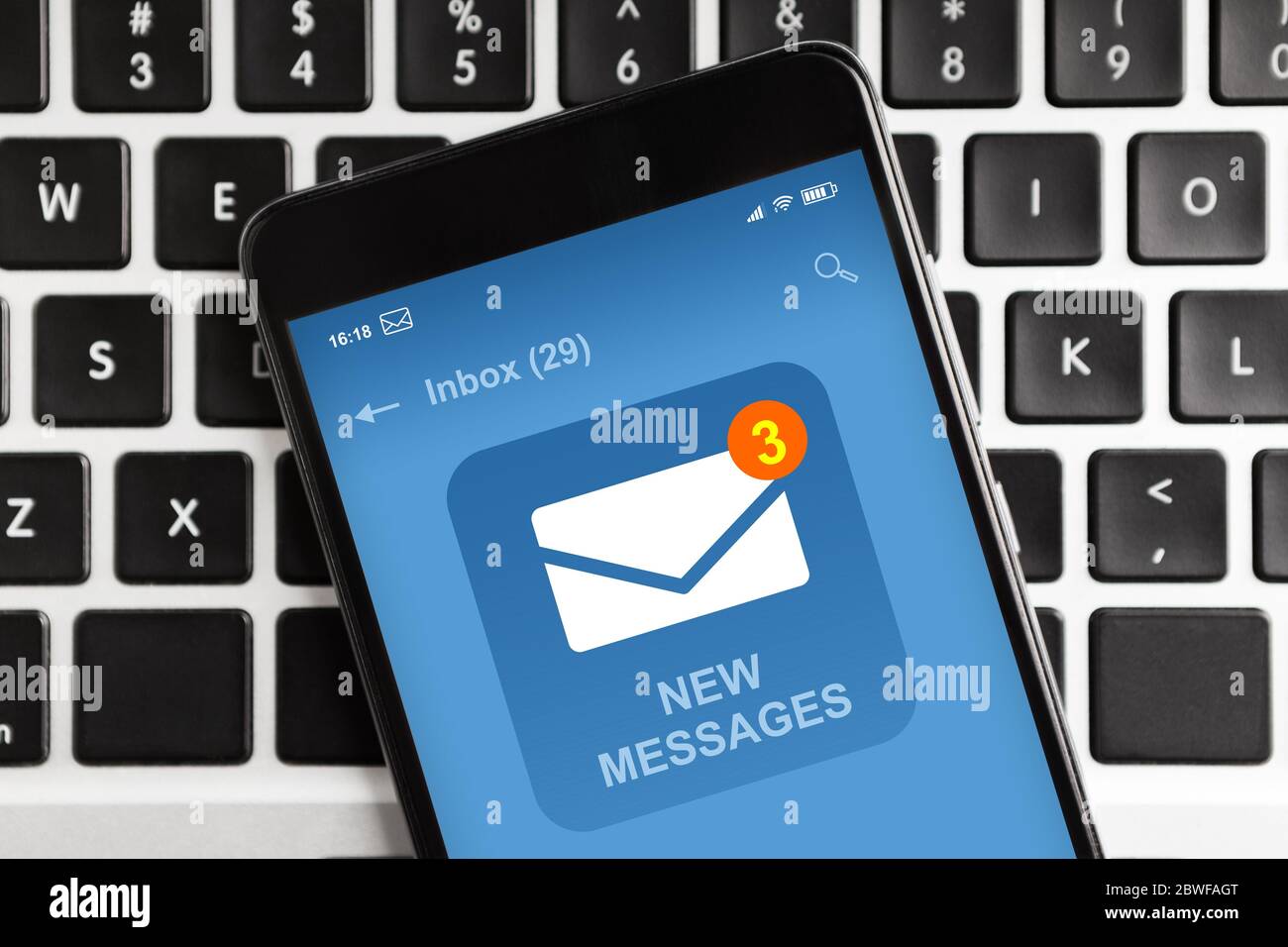Smartphone With New Email Message Notification On Screen Lying On Laptop Keyboard Stock Photo