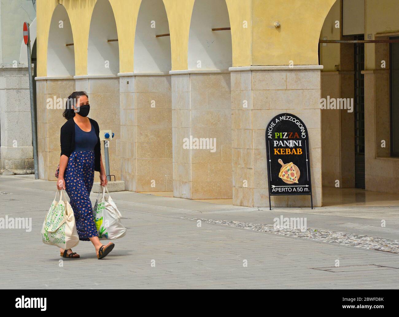 Spilimbergo, Italy - May 31 2020. A woman wearing a face mask walks through the historic centre of Spilimbergo in the Udine province of northern Italy Stock Photo