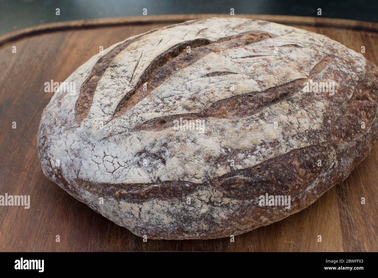 A loaf of sourdough bread on a teak breadboard Stock Photo