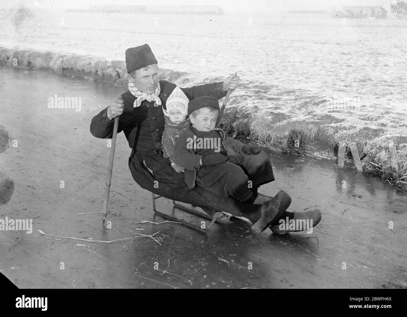 Holland Ice Bound Telegrams from Holland state a hard frost and fierce cold prevail and all canals frozen A considerate father adopts the novel method of tobogganing his children to school on the ice in Holland 10 December 1921 Stock Photo