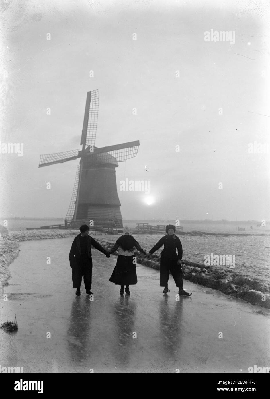 Sun set on the ice A striking picture of young Hollanders still active on the ice while the sun light departs 10 December 1921 Stock Photo
