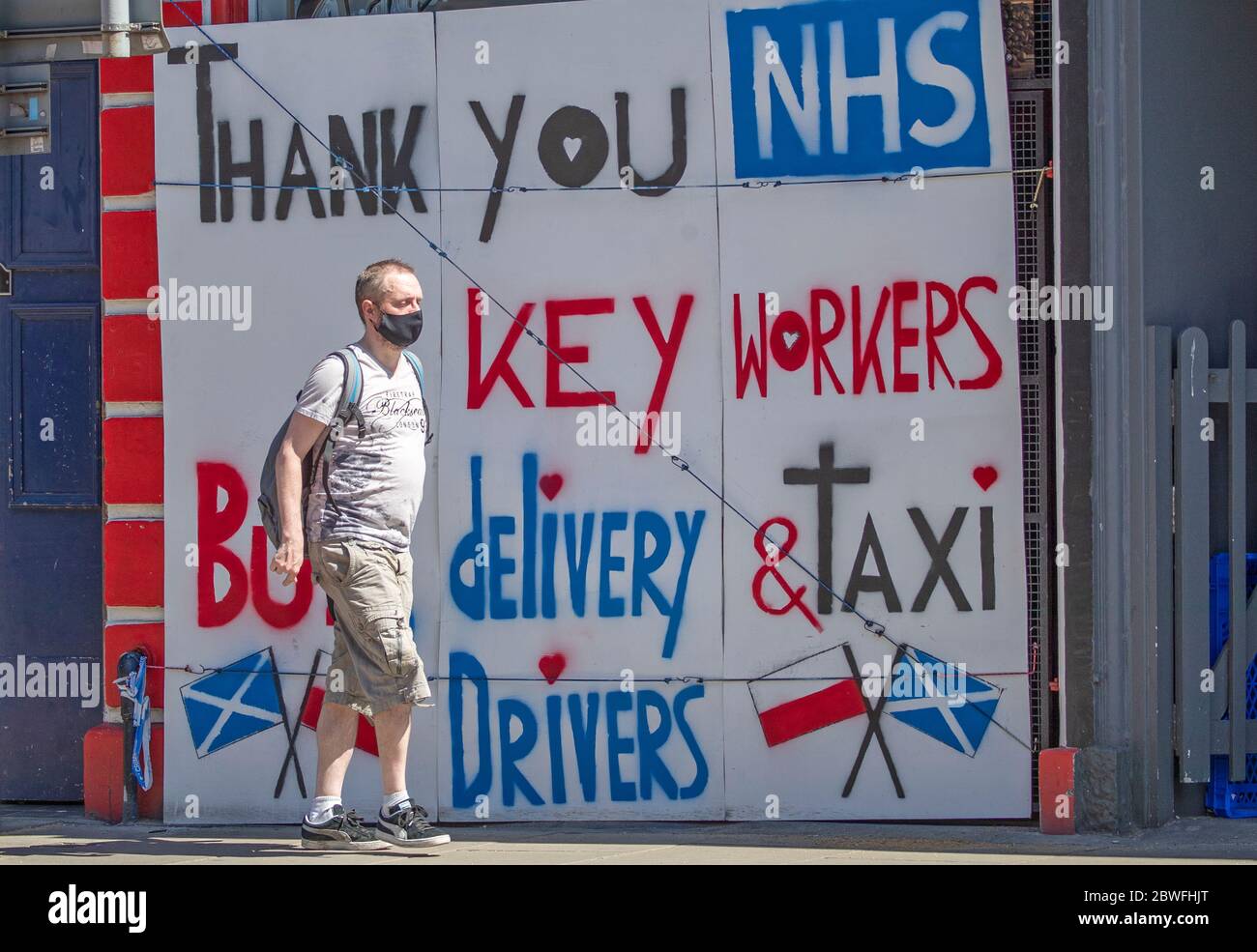A woman cycles past a poster thanking the NHS and keyworkers in Edinburgh, as people can meet family and friends outdoors and play sports such as golf and tennis again as Scotland is moving into phase one of the Scottish Government's plan for gradually lifting lockdown. Stock Photo