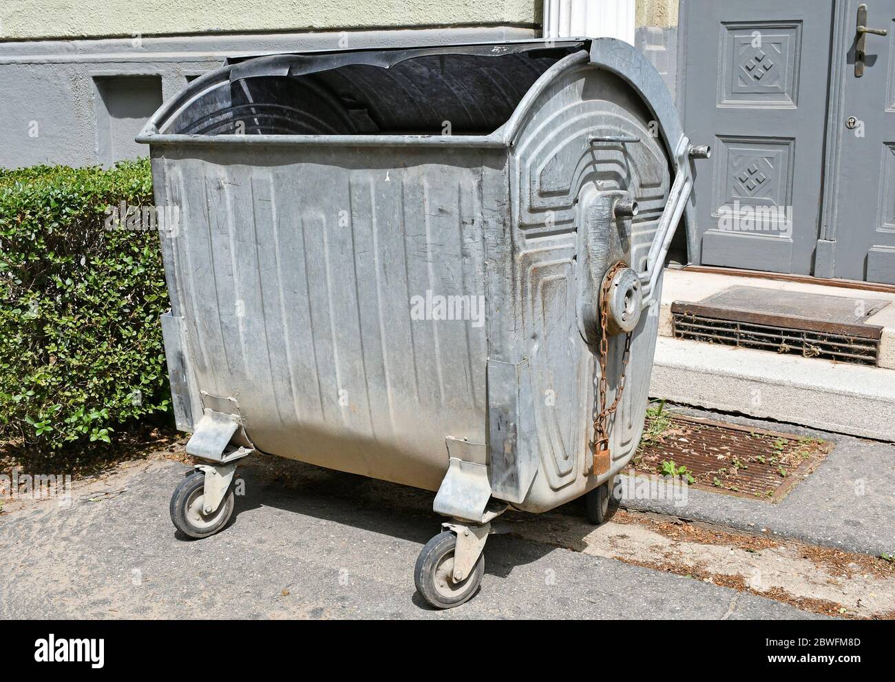 Large green plastic trash cans on city street. Containers on wheels with a  handle to collect commercial and resident trash. Disposal of household and  Stock Photo - Alamy